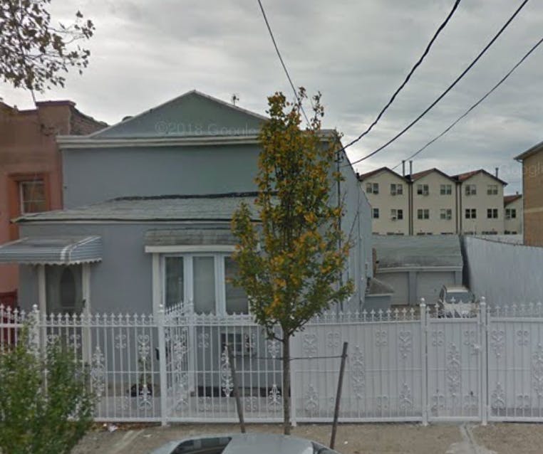 House with a white fence and a tree in front