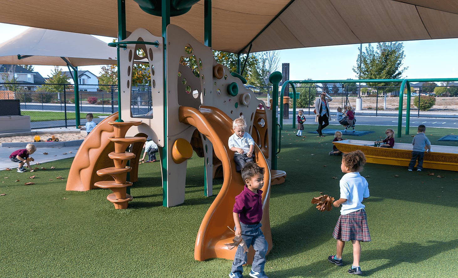 Children playing on a playground structure with slides and swings