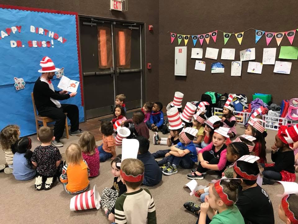 Person in striped hat reading to a group of children