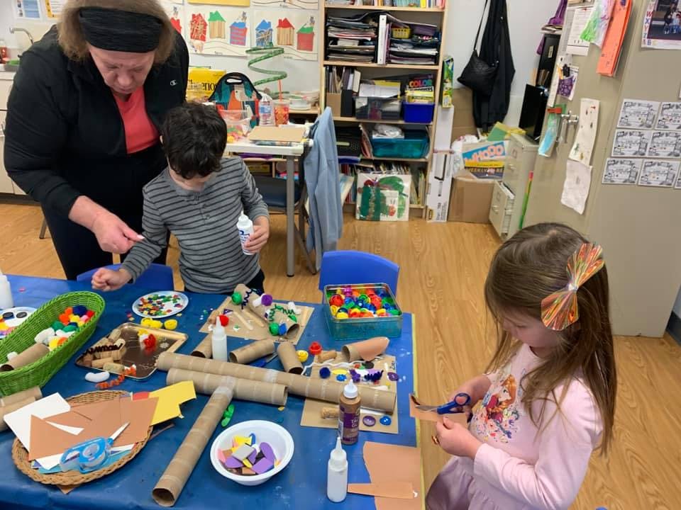 Adult and two children doing crafts in a classroom