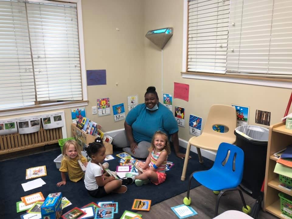 Person and three children sitting on floor in a classroom