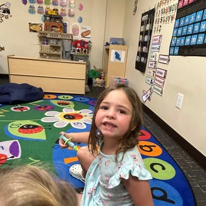Child sitting on a colorful rug in a classroom