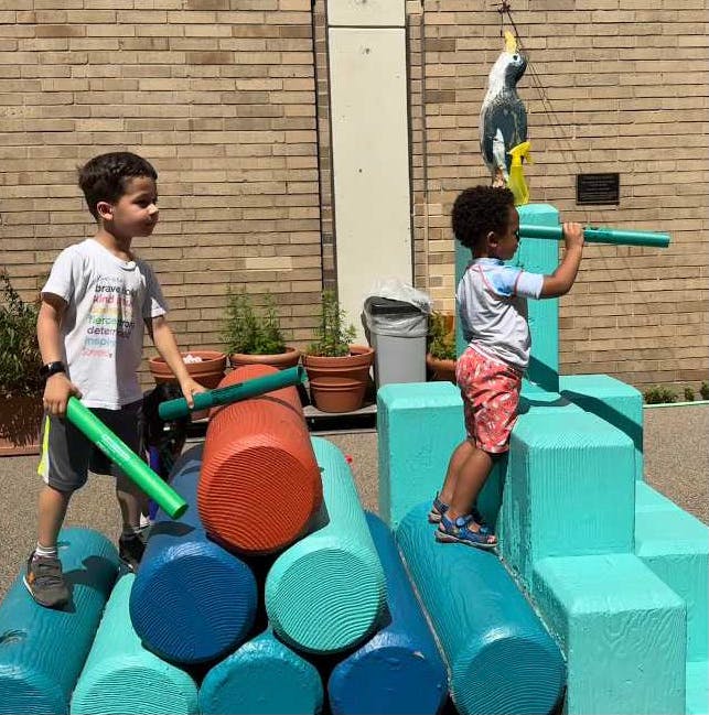 Two children playing on large foam building blocks