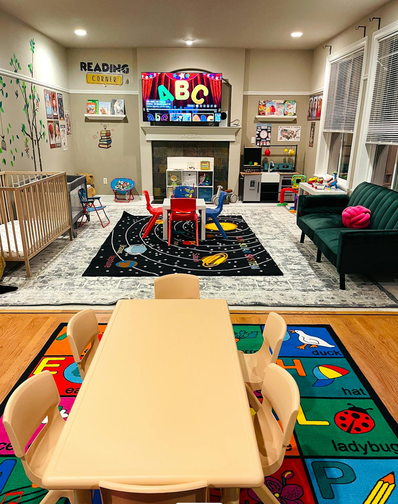 Playroom with crib, small tables and chairs, and a TV displaying ABC