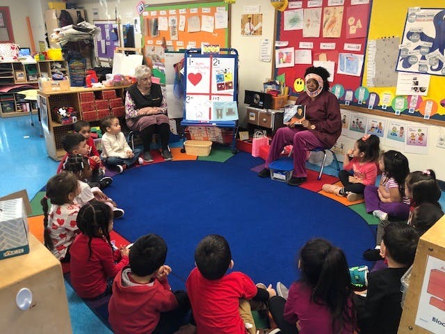 Adults reading to children sitting in a circle in a classroom