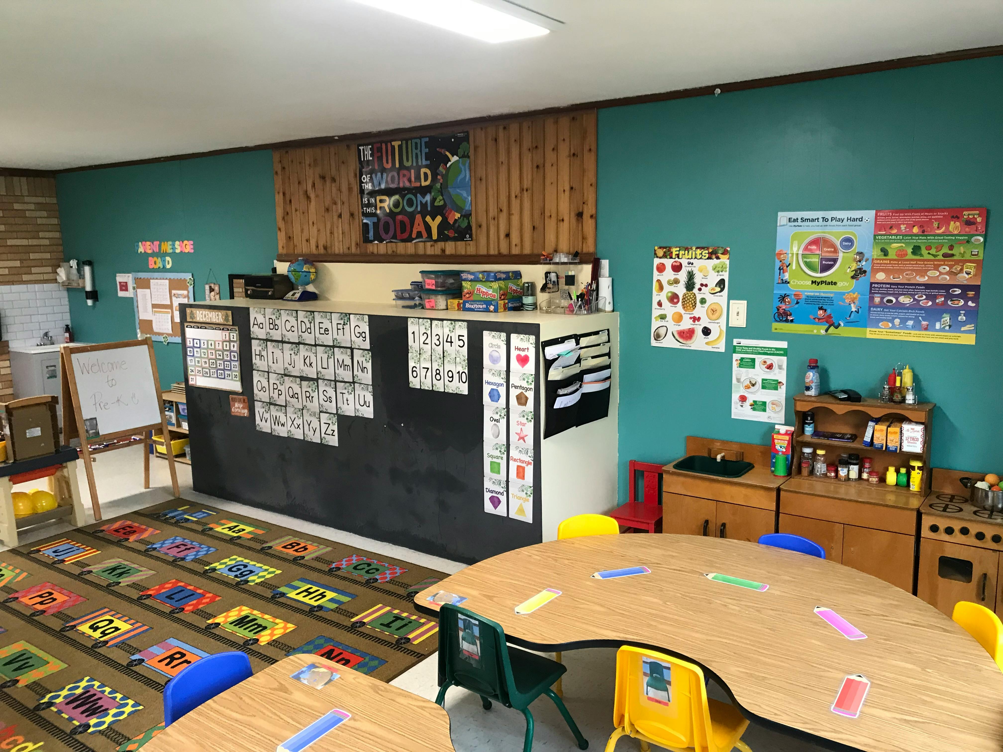 Classroom with tables, chairs, and educational posters on the walls