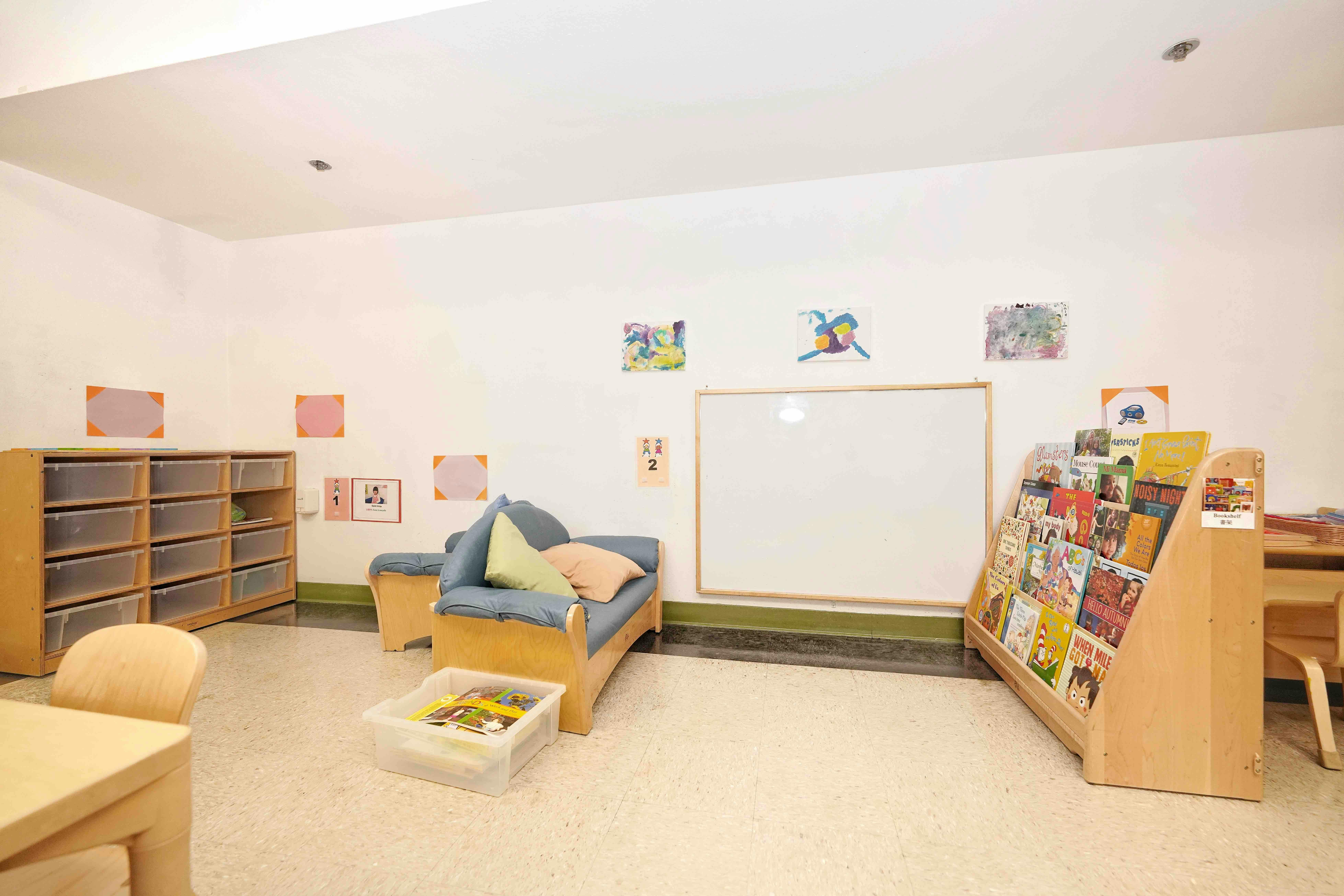 Childcare room with a bookshelf, a small couch, and a whiteboard