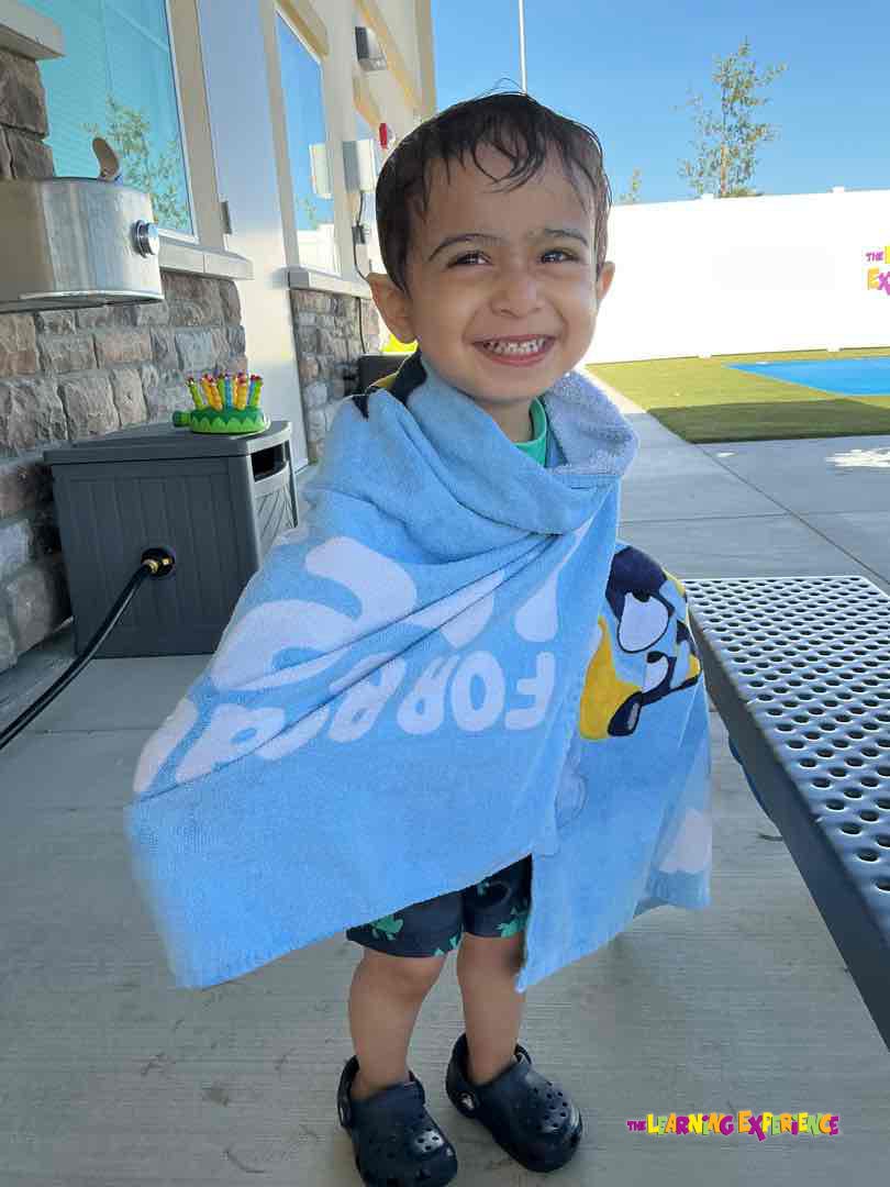 Child wrapped in a blue towel standing outdoors