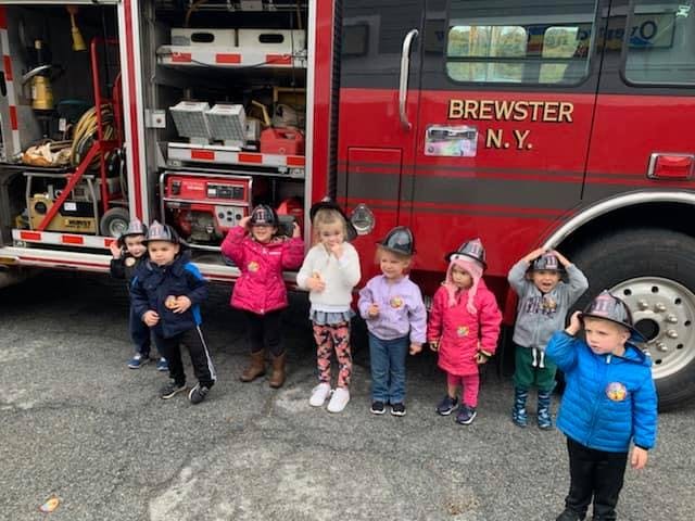 Children wearing firefighter helmets standing in front of a fire truck