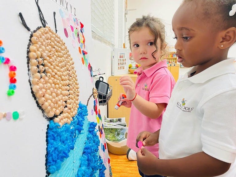 Two children looking at a butterfly art project on a wall
