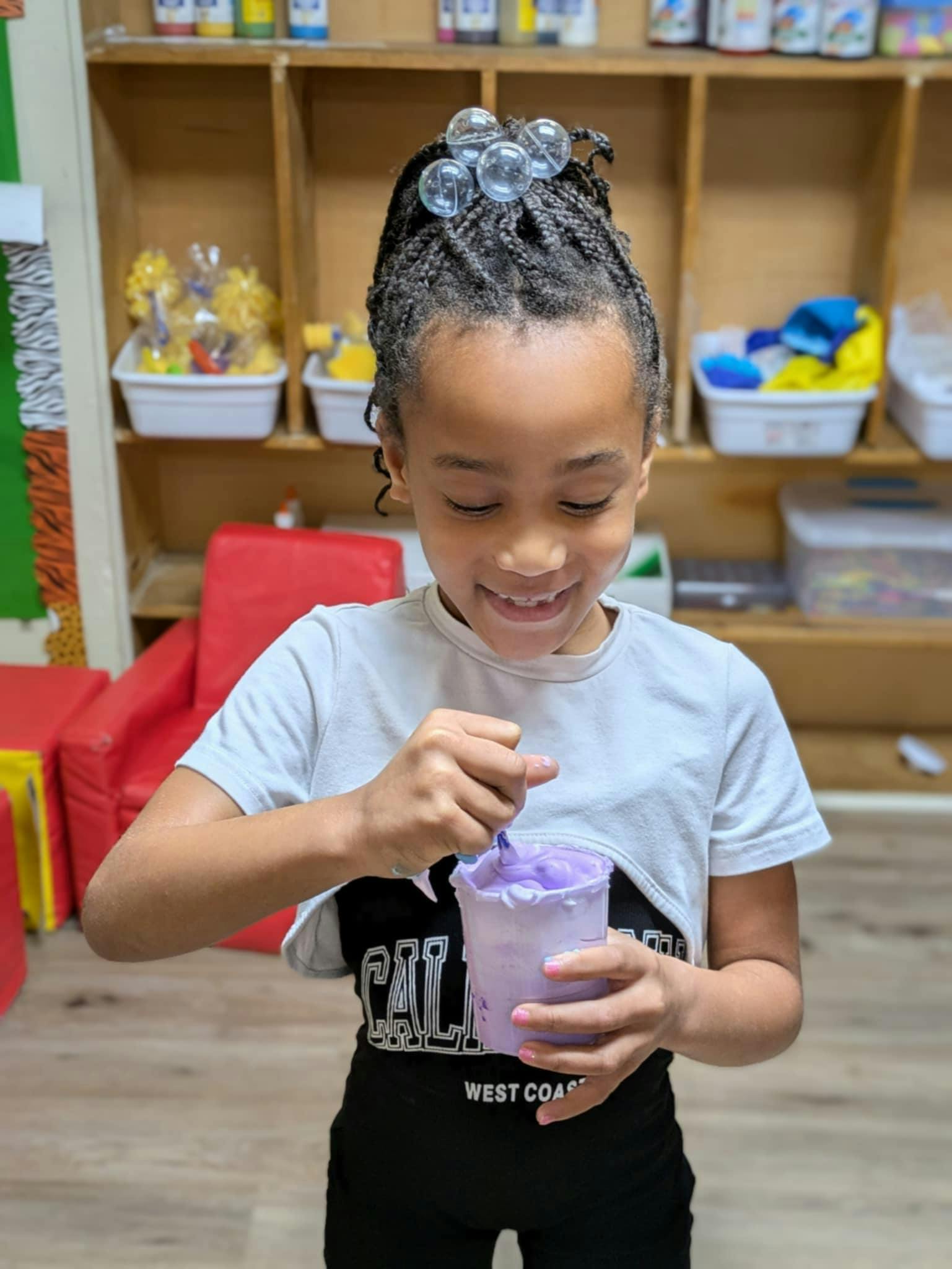 Child stirring purple slime in a cup