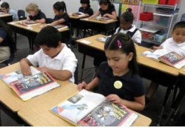Children reading books at desks in a classroom