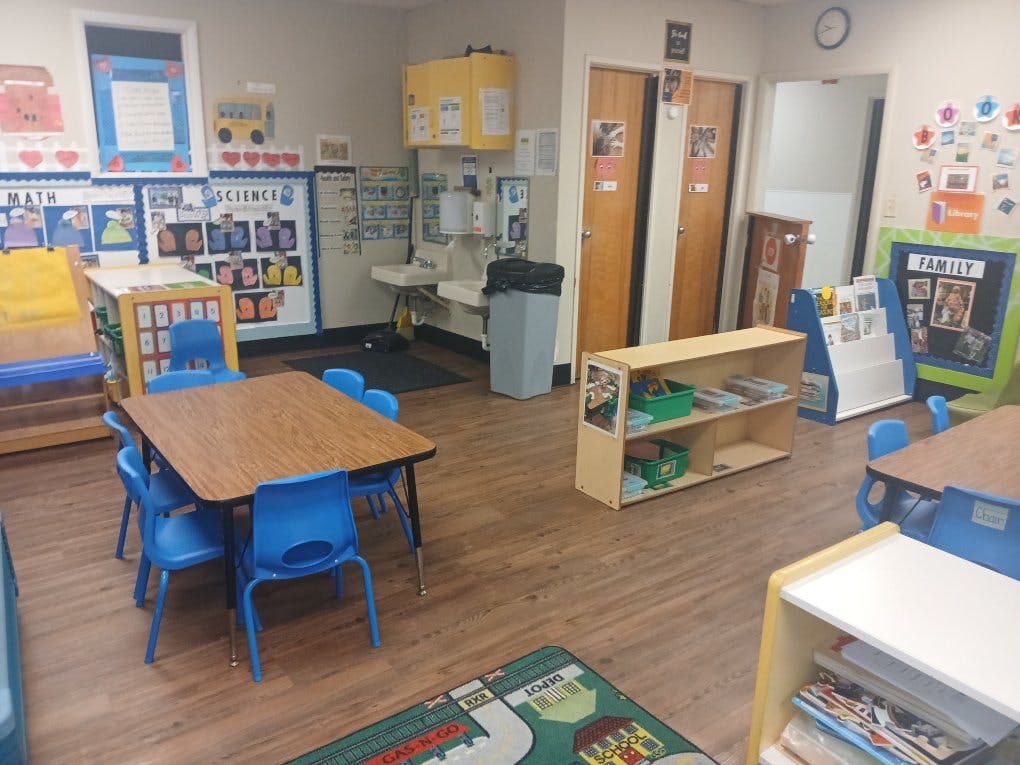 Classroom with small tables and chairs, shelves, and educational decorations on walls
