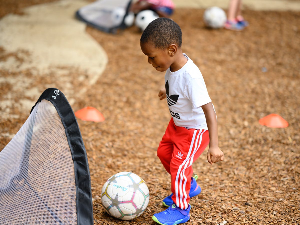 Child playing soccer with a ball and a small goal
