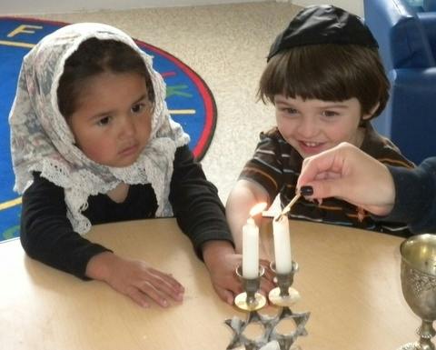 Two children lighting candles on a table
