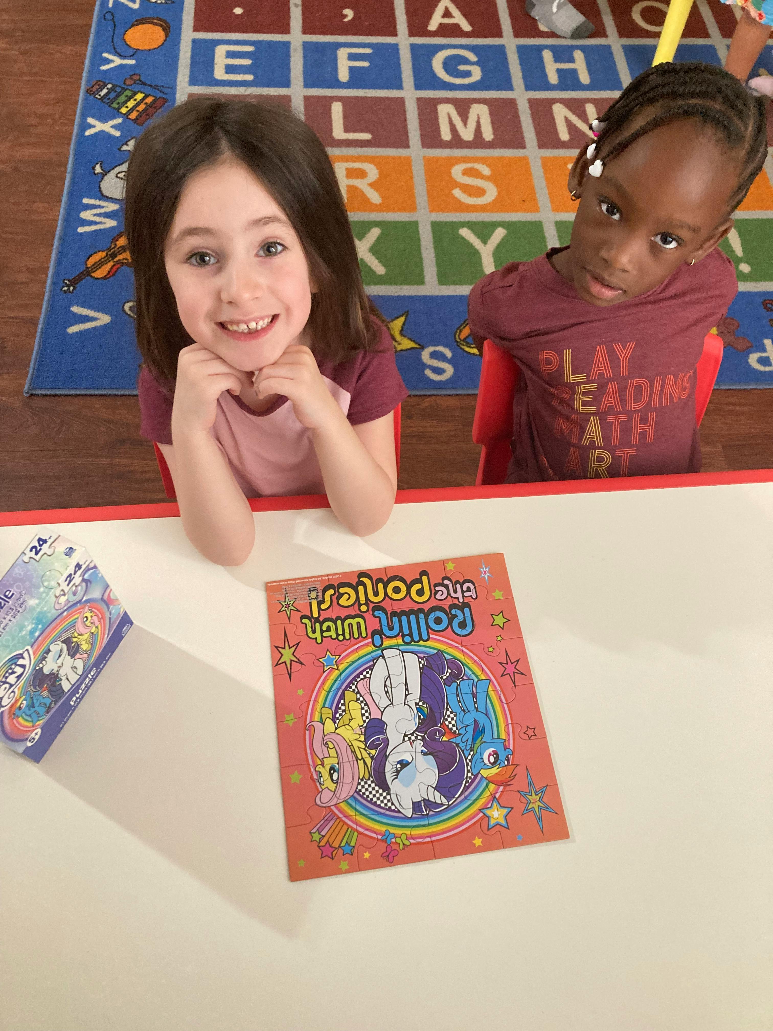 Two children sitting at a table with a My Little Pony puzzle