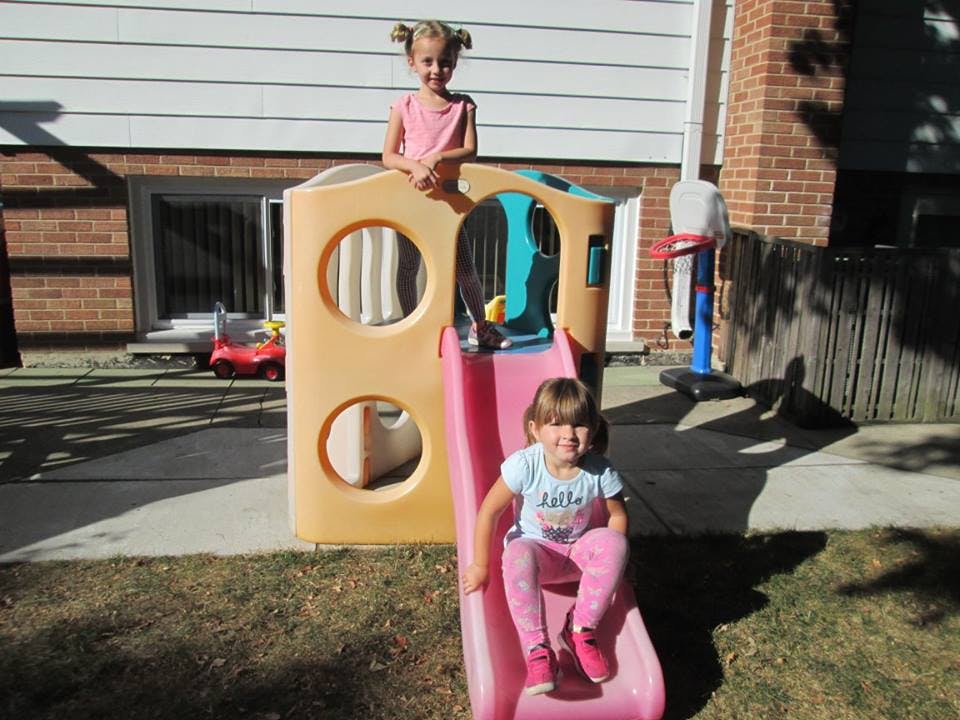 Two children on a pink and tan play slide