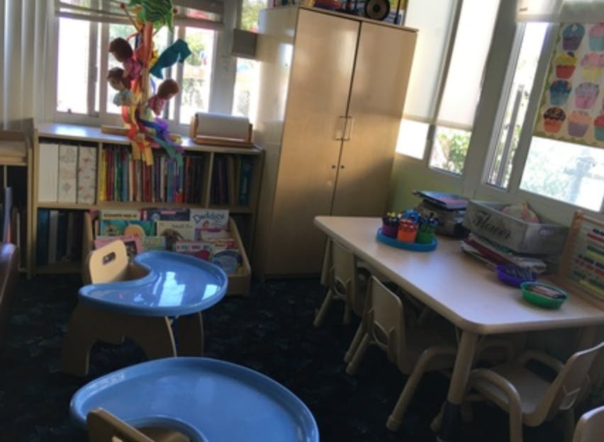 Classroom with small tables and chairs, bookshelves, and windows