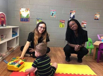 Two people and a child playing with a toy on the floor