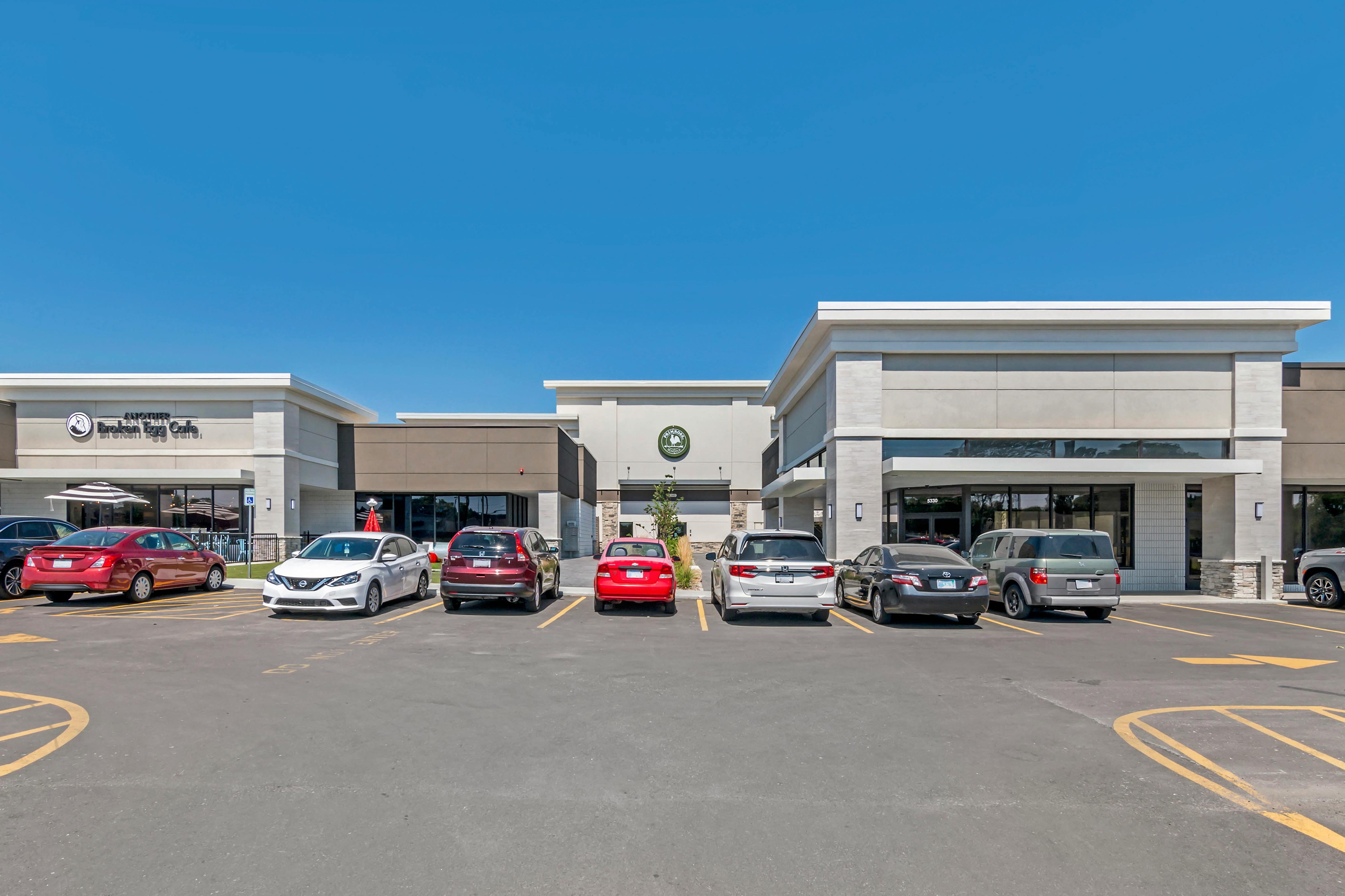 Parking lot with several cars in front of a modern commercial building facade