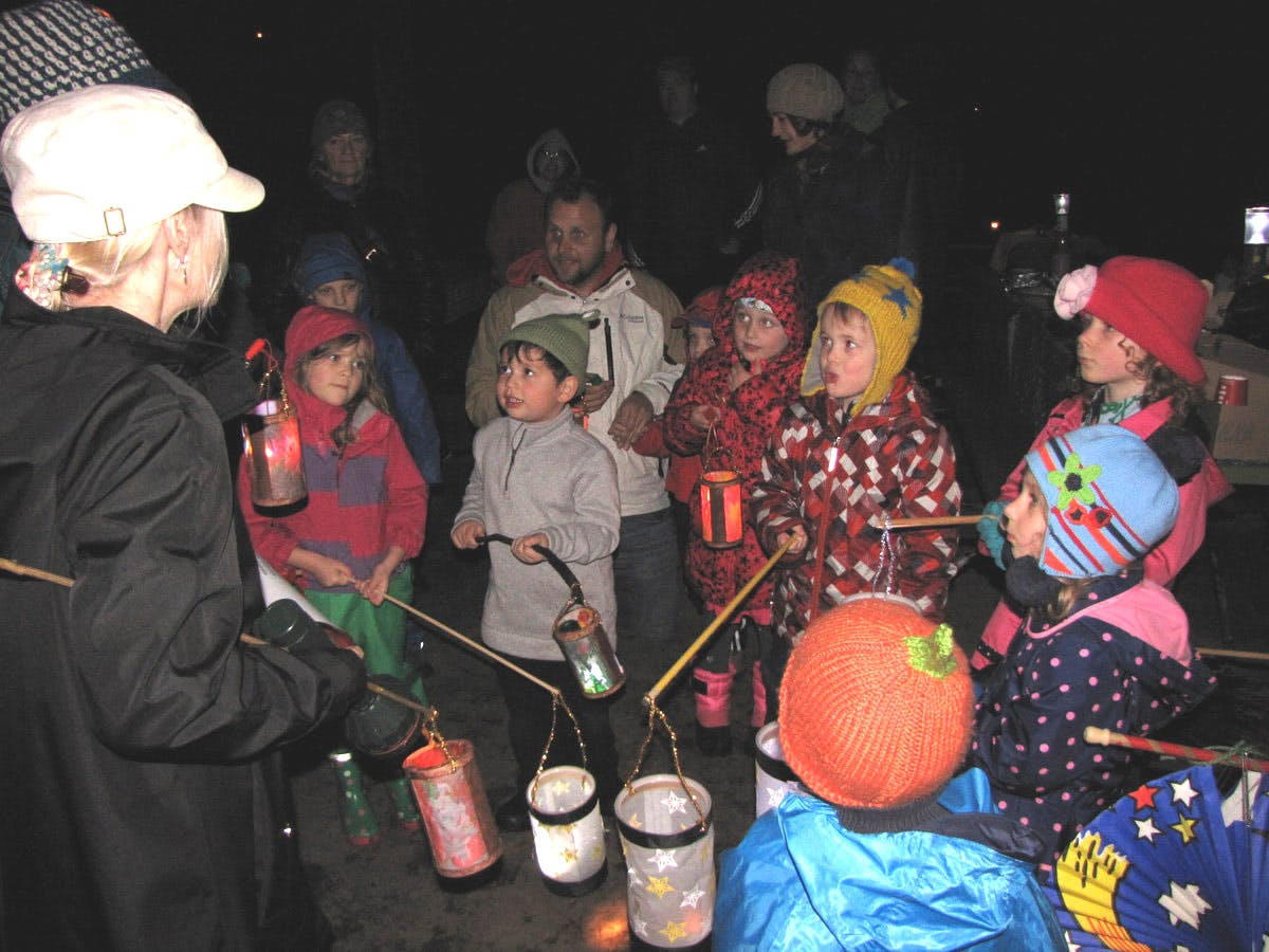 People and children holding lanterns in the dark