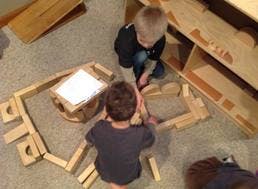 Two children playing with wooden blocks on the floor