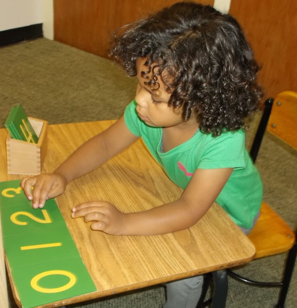 Child at a desk with a green mat with numbers