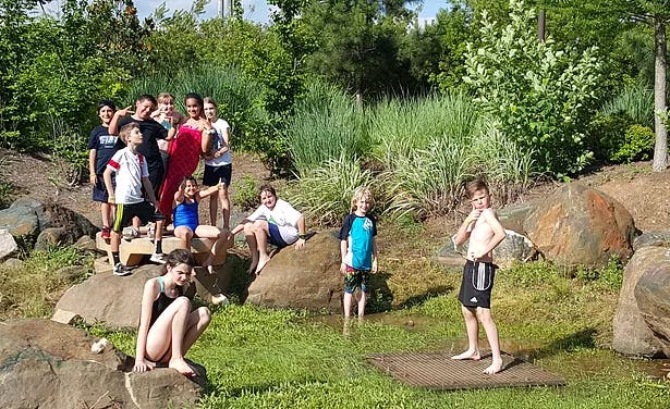 Group of children and teens playing outdoors among rocks and grass