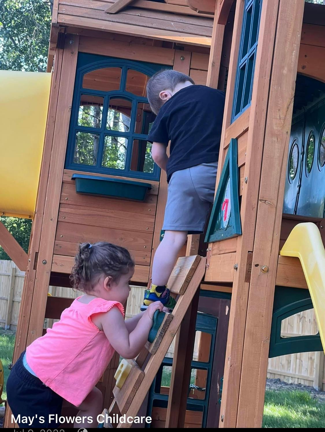 Two children climbing a wooden playset