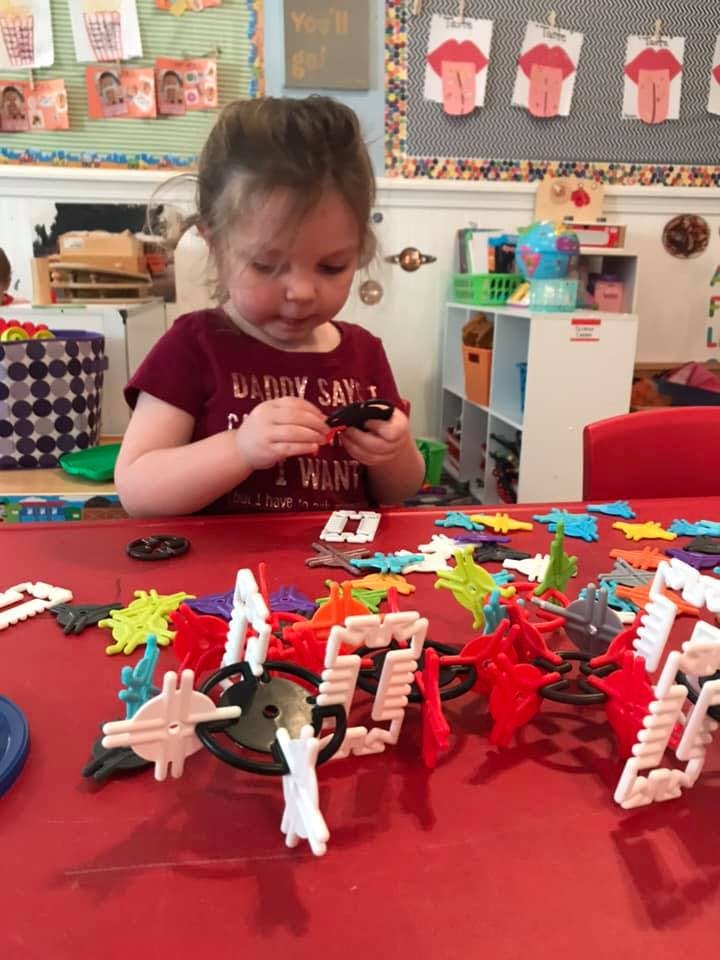Child playing with building toys at a red table