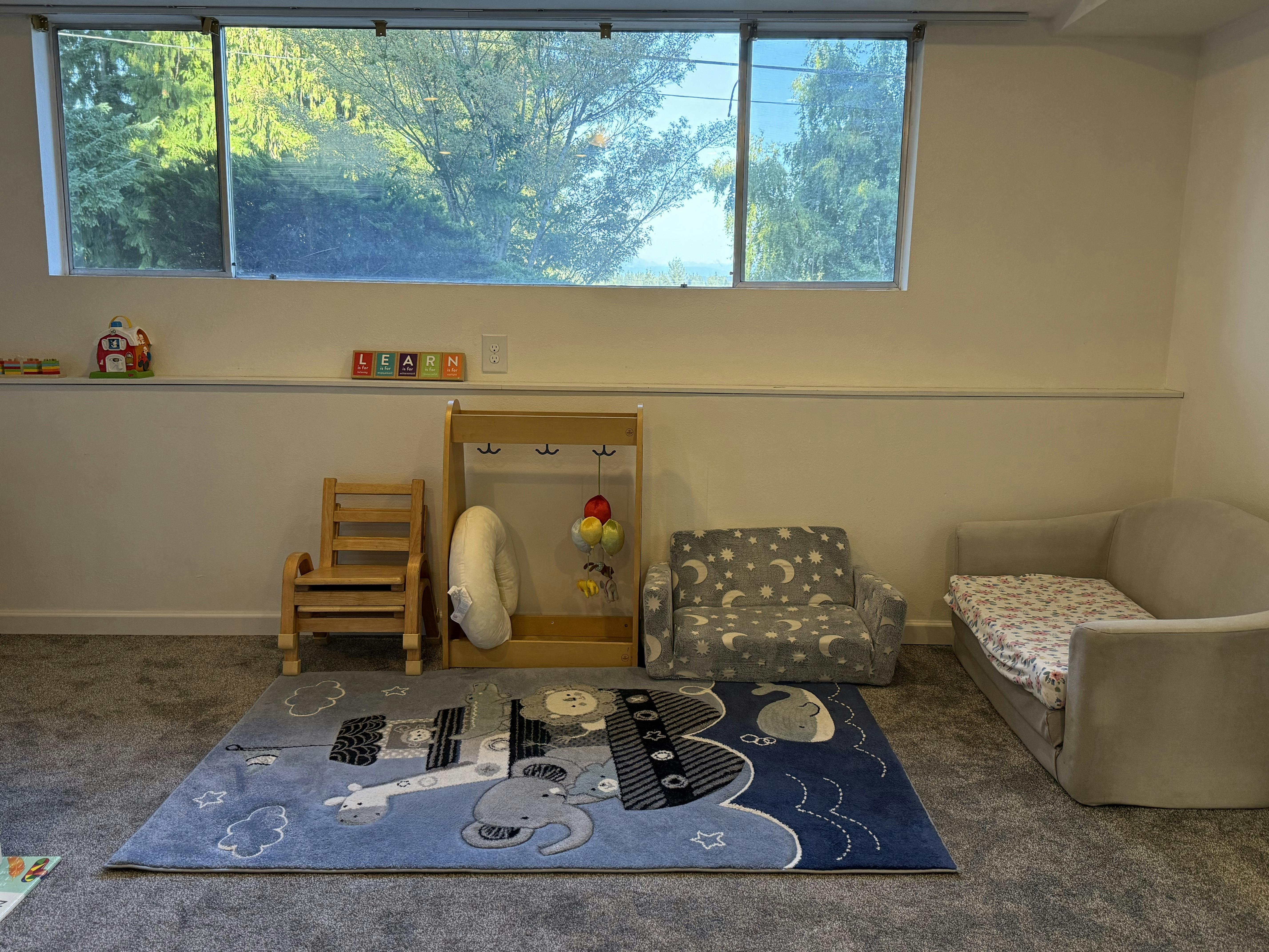 Child's play area with a rug, small chairs, and a window overlooking trees