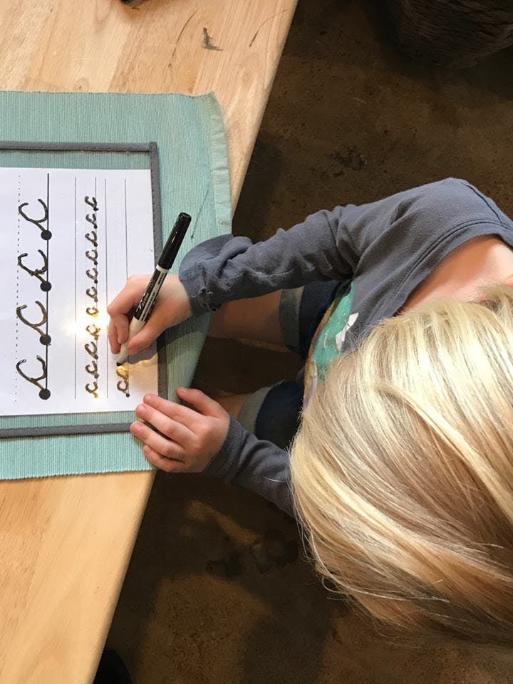 Child writing cursive letters on a worksheet