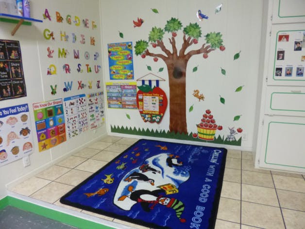 Classroom with alphabet letters, posters, tree mural, and blue rug