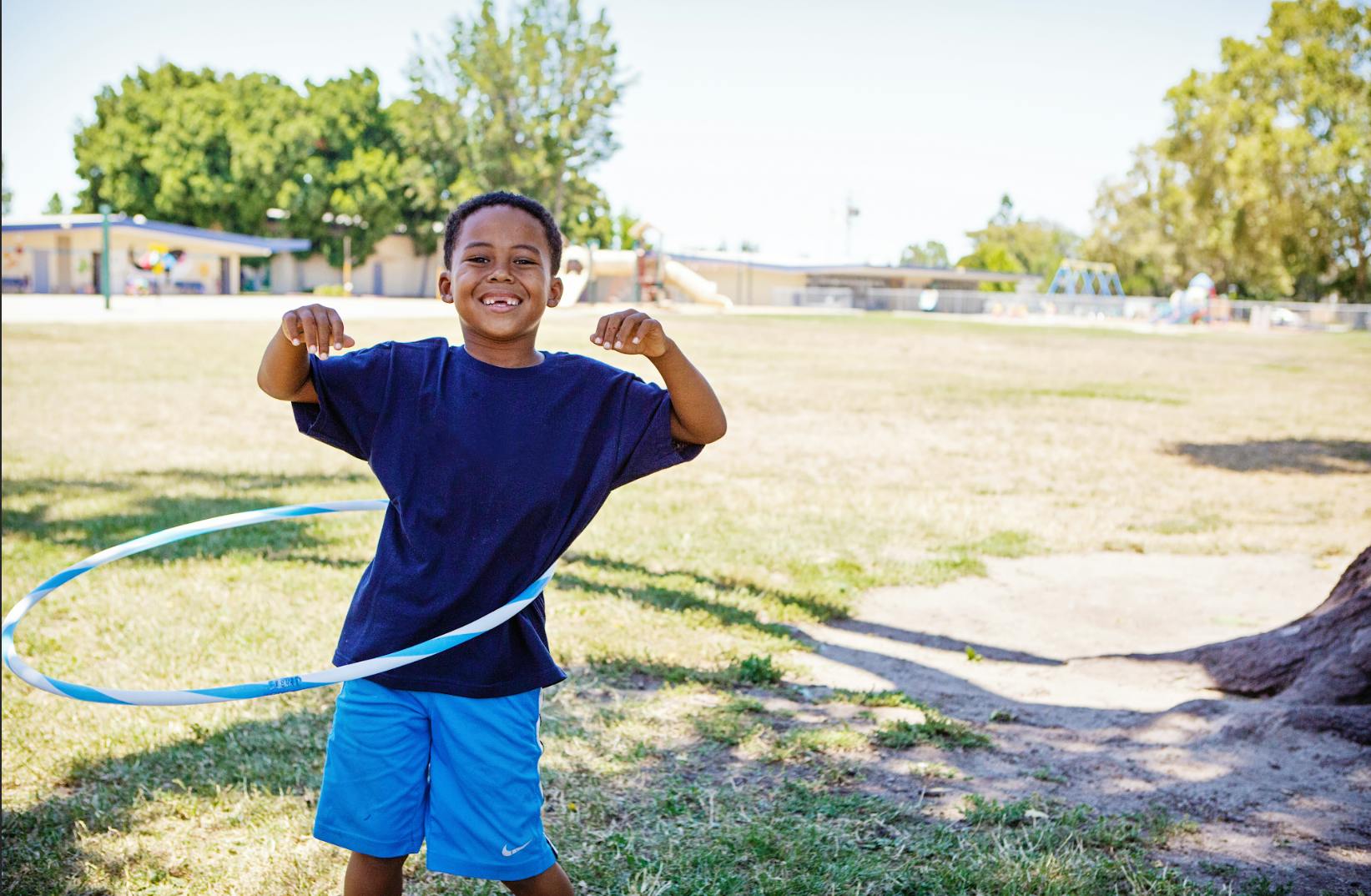 Child with a hula hoop around their waist, flexing their arms