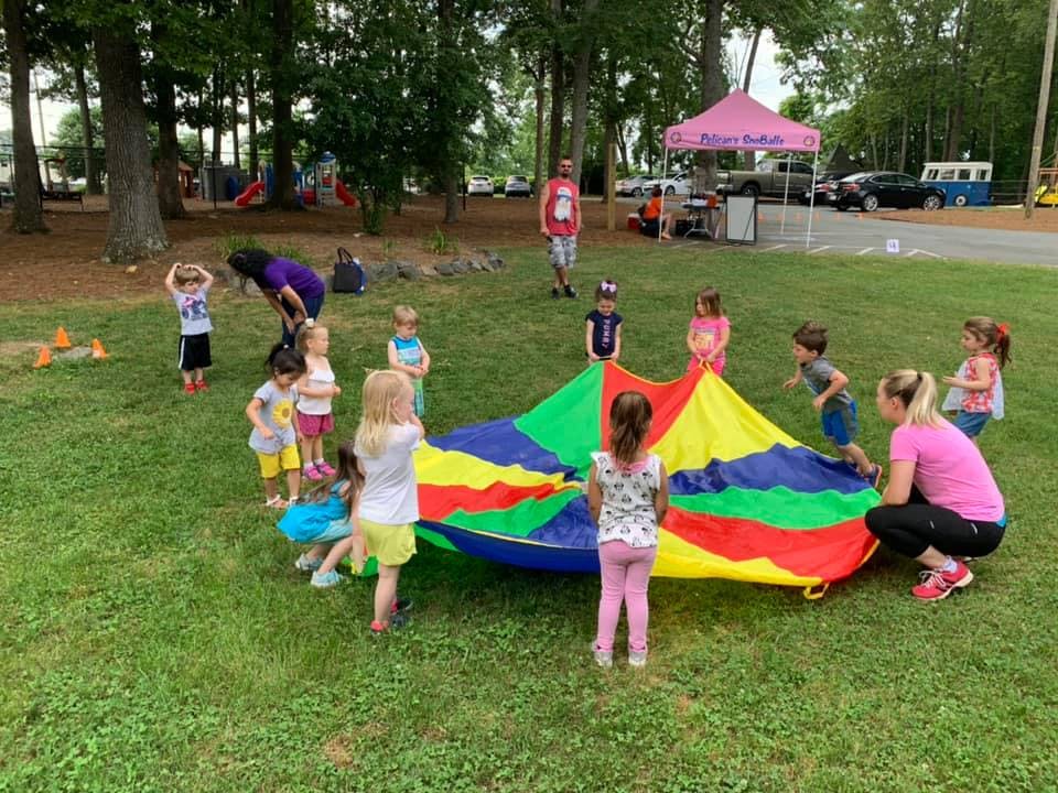 Children and adults playing with a colorful parachute on grass