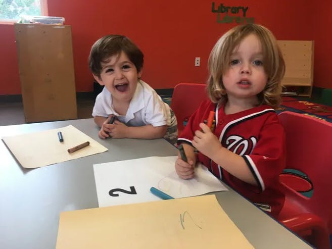 Two children drawing with crayons at a table