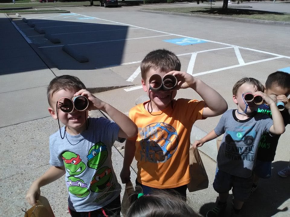 Children looking through cardboard tube binoculars outdoors