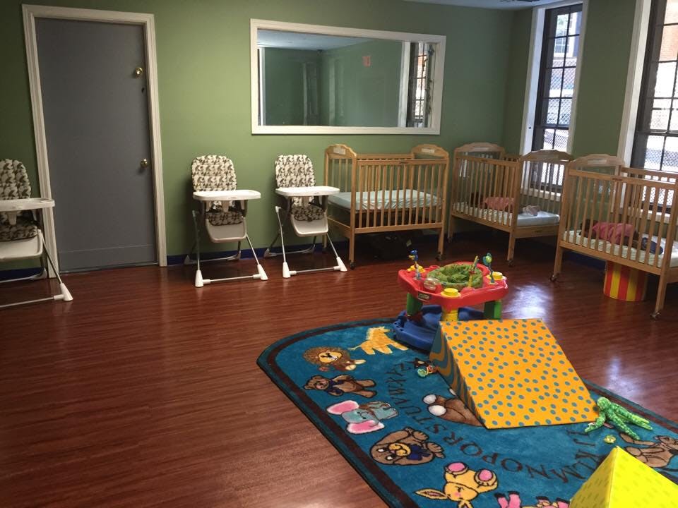 Nursery room with cribs, high chairs, and a play mat