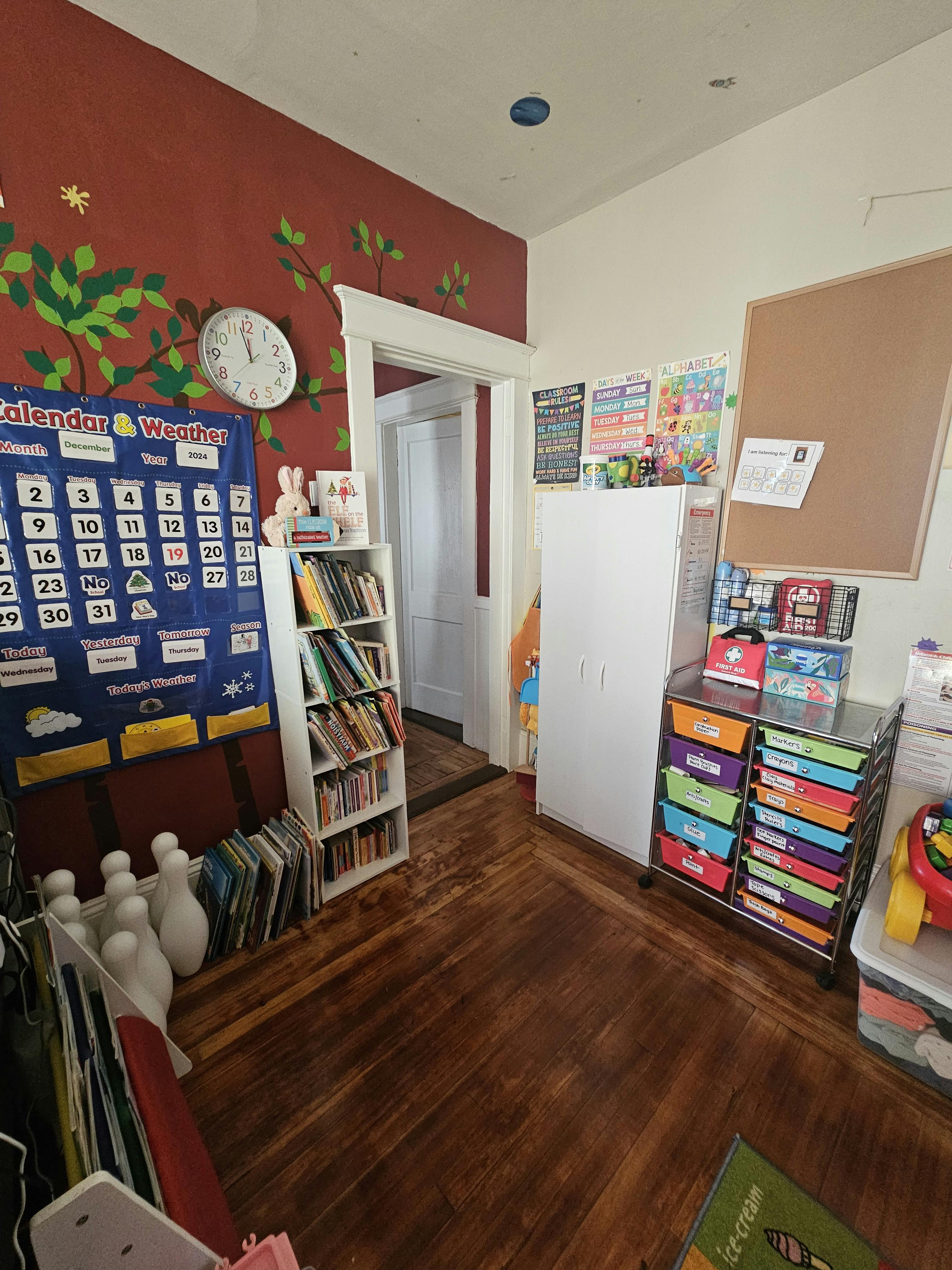 Classroom with a calendar, bookshelf, and storage drawers