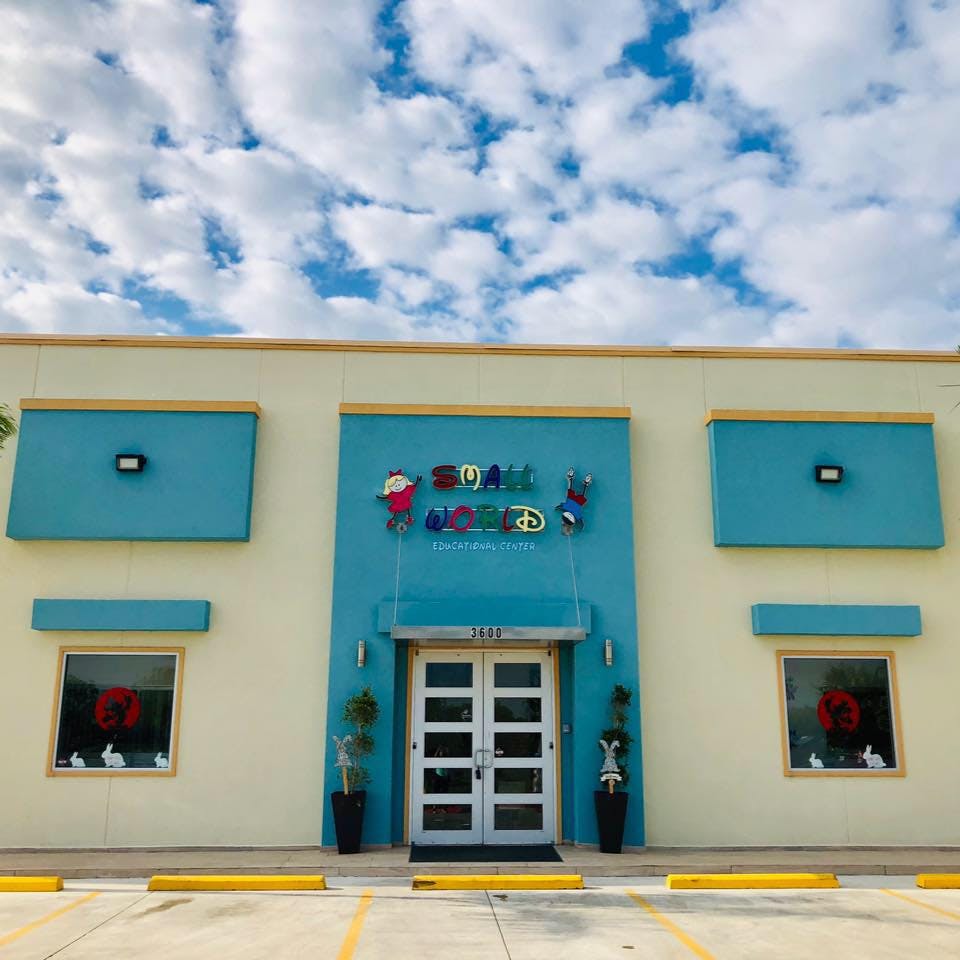 Building exterior with a blue facade and double doors under a sign