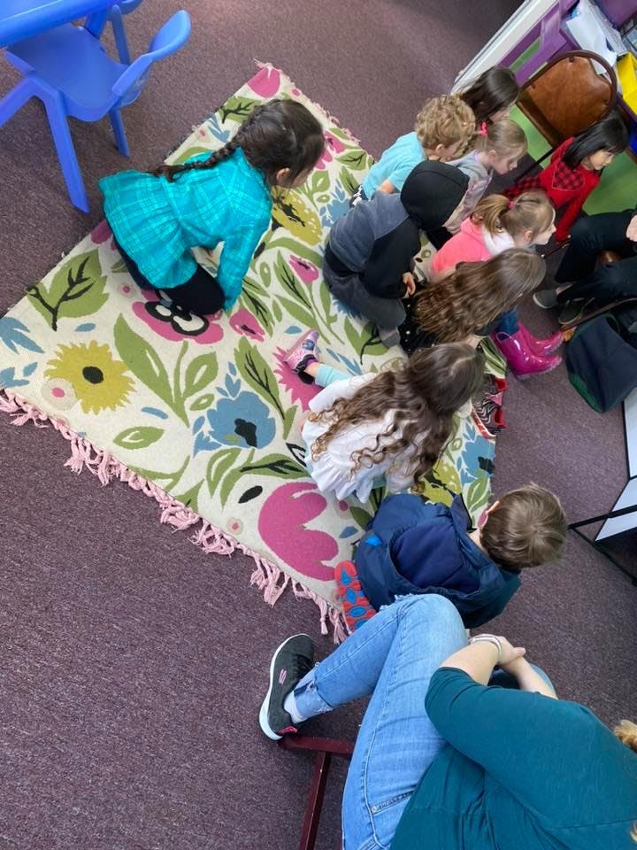 Children sitting on a colorful rug in a classroom