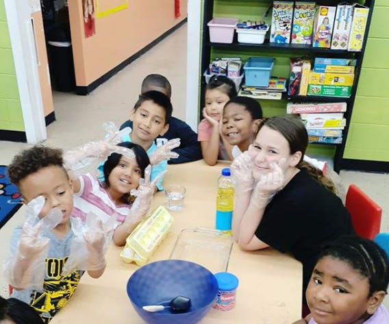 Children wearing gloves at a table with bowls and bottles