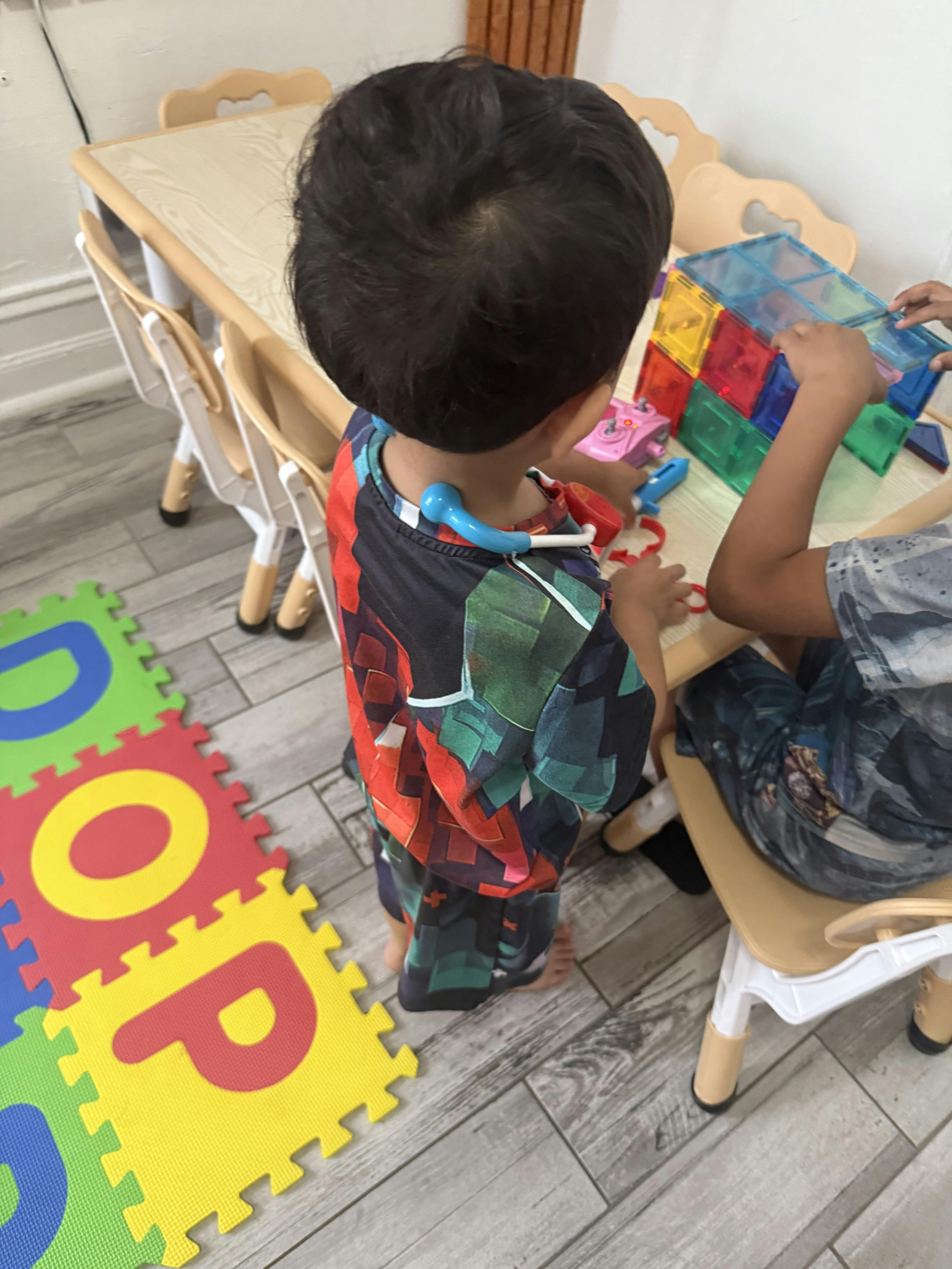 Two children playing with magnetic blocks at a small table