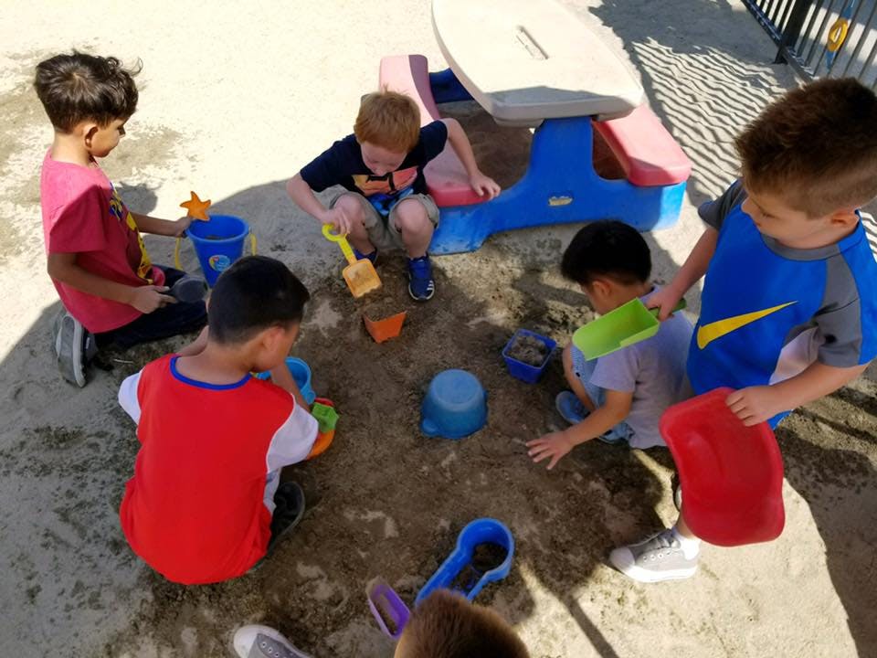 Children playing in a sandbox with toys
