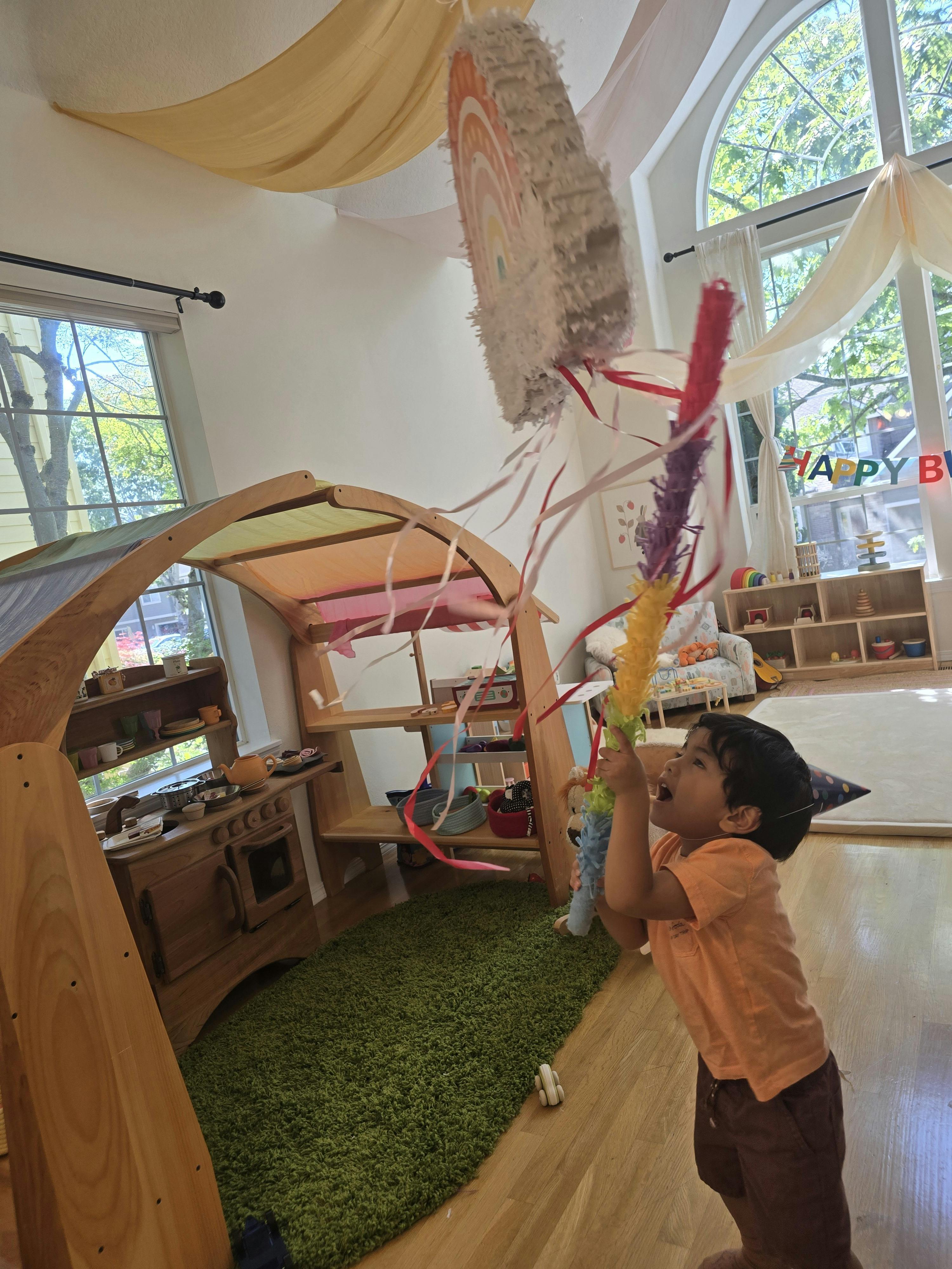 Child hitting a pinata in a playroom