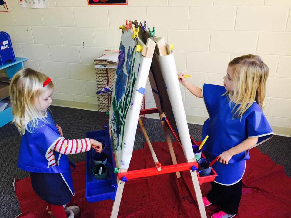 Two children painting at an easel