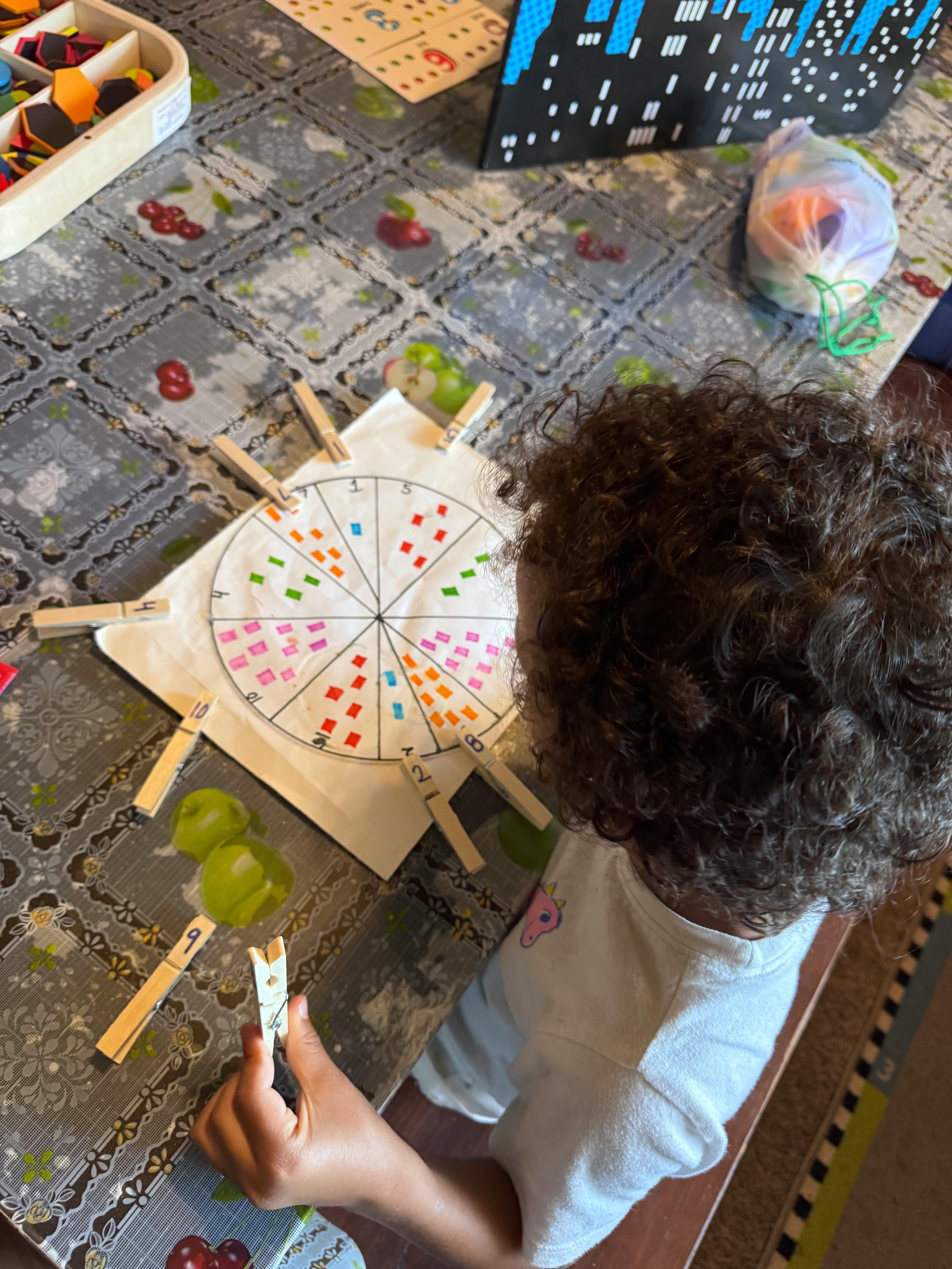 Child playing with a colorful wheel and clothespins