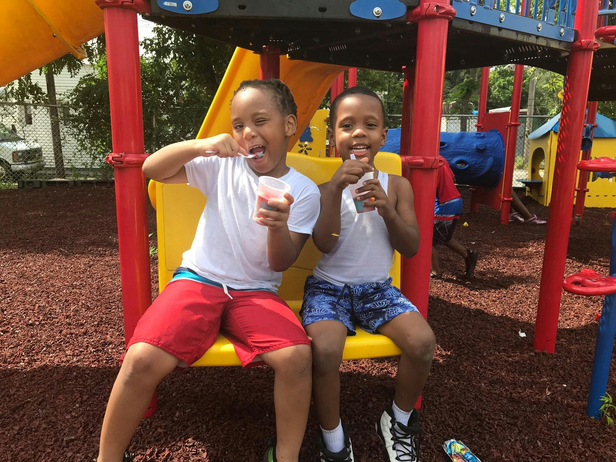 Two children eating snacks on a playground