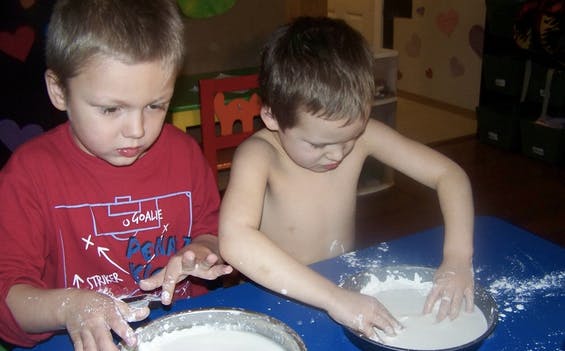 Two children playing with white powder in bowls