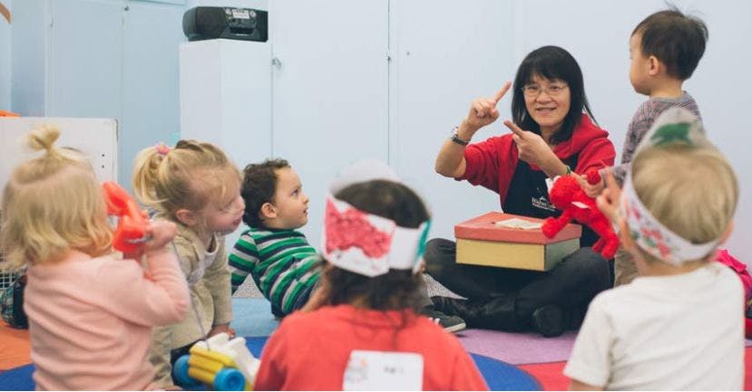 Adult person sitting on floor with children, gesturing with adult gesturing